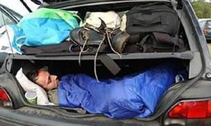  A person asleep in the trunk of a vehicle.